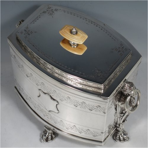 An Antique Victorian Silver Plated biscuit box, having a Neoclassical style rectangular shaped body with straight sides, applied bead-edged borders, with two bands of hand-engraving above and below a vacant cartouche, a hinged lid with ivory finial, two cast lion-mask ring handles, and all sitting on four cast lions-paw feet. Made in ca. 1880. The dimensions of this fine hand-made silver-plated biscuit boxr are height 18 cms (7 inches), length 21 cms (8.25 inches), and width 15 cms (6 inches).