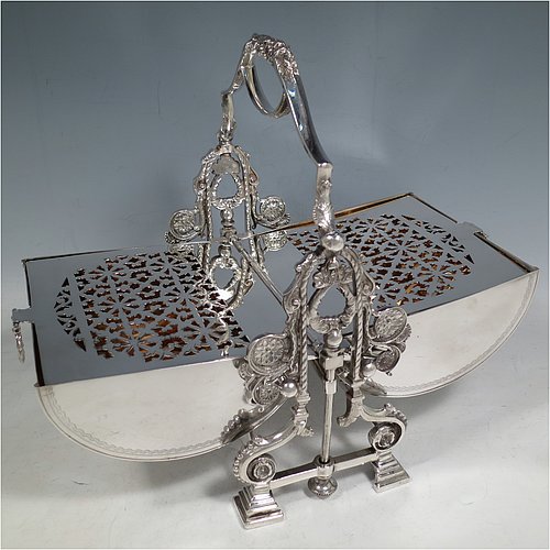 A very pretty Antique Victorian Silver Plated folding biscuit box, having an oval barrel-shaped body with beautiful hand-engraved floral and bird decoration, with straight sides and applied gadroon borders, sitting in a cast floral style mechanical frame with carrying handle, all sitting on four stepped feet, and with original gold-gilt interior with hand-pierced dividers. Made in ca. 1880. The dimensions of this fine hand-made silver-plated folding biscuit box are height 25.5 cms (10 inches), length fully opened 30.5 cms (12 inches), and width 20 cms (8 inches).    