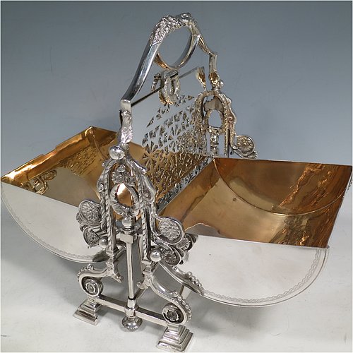 A very pretty Antique Victorian Silver Plated folding biscuit box, having an oval barrel-shaped body with beautiful hand-engraved floral and bird decoration, with straight sides and applied gadroon borders, sitting in a cast floral style mechanical frame with carrying handle, all sitting on four stepped feet, and with original gold-gilt interior with hand-pierced dividers. Made in ca. 1880. The dimensions of this fine hand-made silver-plated folding biscuit box are height 25.5 cms (10 inches), length fully opened 30.5 cms (12 inches), and width 20 cms (8 inches).    