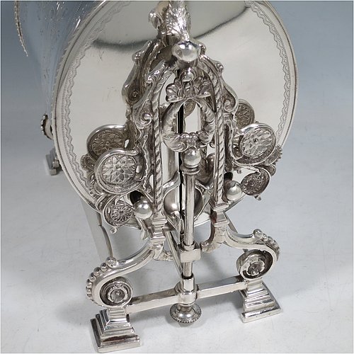 A very pretty Antique Victorian Silver Plated folding biscuit box, having an oval barrel-shaped body with beautiful hand-engraved floral and bird decoration, with straight sides and applied gadroon borders, sitting in a cast floral style mechanical frame with carrying handle, all sitting on four stepped feet, and with original gold-gilt interior with hand-pierced dividers. Made in ca. 1880. The dimensions of this fine hand-made silver-plated folding biscuit box are height 25.5 cms (10 inches), length fully opened 30.5 cms (12 inches), and width 20 cms (8 inches).    