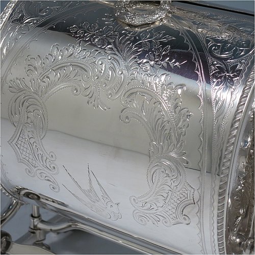 A very pretty Antique Victorian Silver Plated folding biscuit box, having an oval barrel-shaped body with beautiful hand-engraved floral and bird decoration, with straight sides and applied gadroon borders, sitting in a cast floral style mechanical frame with carrying handle, all sitting on four stepped feet, and with original gold-gilt interior with hand-pierced dividers. Made in ca. 1880. The dimensions of this fine hand-made silver-plated folding biscuit box are height 25.5 cms (10 inches), length fully opened 30.5 cms (12 inches), and width 20 cms (8 inches).    