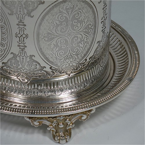 An Antique Victorian Silver Plated biscuit box, having an oval body with straight sides and very pretty hand-chased floral work, a hinged slightly domed lid with a thumb-piece, and all sitting on a hand-pierced attached plate with four cast foliate feet. Made by Roberts and Belk of Sheffield in ca. 1880. The dimensions of this fine hand-made antique silver-plated biscuit box are height 15 cms (6 inches), length 20 cms (8 inches), and width 17 cms (6.75 inches).    