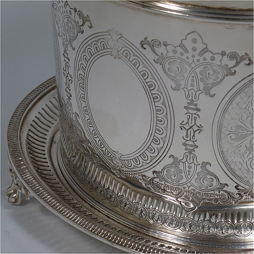 An Antique Victorian Silver Plated biscuit box, having an oval body with straight sides and very pretty hand-chased floral work, a hinged slightly domed lid with a thumb-piece, and all sitting on a hand-pierced attached plate with four cast foliate feet. Made by Roberts and Belk of Sheffield in ca. 1880. The dimensions of this fine hand-made antique silver-plated biscuit box are height 15 cms (6 inches), length 20 cms (8 inches), and width 17 cms (6.75 inches).    