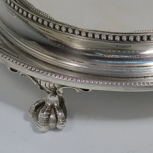 An Antique Victorian Silver Plated biscuit box, having a round body with applied bead-edged borders, straight sides and hand-chased swags of bead-work in a neoclassical style, a hinged domed lid with cast finial, and all sitting on an attached plate with three cast claw and ball feet. Made by James Thompson of Sheffield in ca. 1880. The dimensions of this fine hand-made antique silver-plated biscuit box are height 18 cms (7 inches), and diameter at base 18 cms (7 inches). Please note that this item is crested.