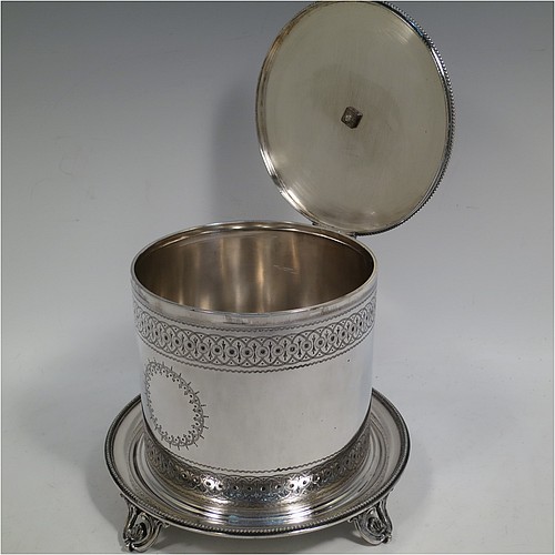 A very pretty Antique Victorian Silver Plated biscuit box, having a round body with straight sides and applied bead-edged borders, with very pretty hand-engraved bands of geometrical and floral work, a hinged flat lid with bone finial, and all sitting on an attached plate with four cast scroll and shell feet. Made by Elkington and Co., of Sheffield in ca. 1880. The dimensions of this fine hand-made antique silver-plated biscuit box are height 16 cms (6.3 inches), and diameter at base 18 cms (7 inches).