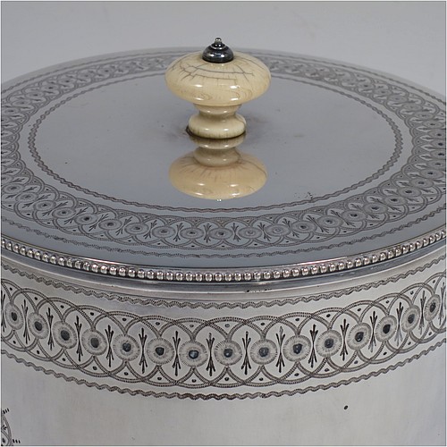 A very pretty Antique Victorian Silver Plated biscuit box, having a round body with straight sides and applied bead-edged borders, with very pretty hand-engraved bands of geometrical and floral work, a hinged flat lid with bone finial, and all sitting on an attached plate with four cast scroll and shell feet. Made by Elkington and Co., of Sheffield in ca. 1880. The dimensions of this fine hand-made antique silver-plated biscuit box are height 16 cms (6.3 inches), and diameter at base 18 cms (7 inches).