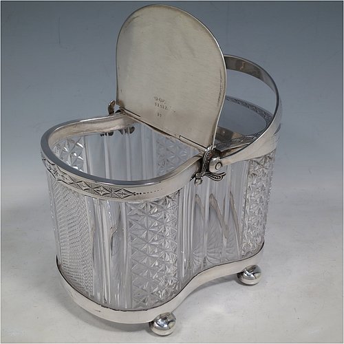 An Antique Victorian silver plated and cut crystal biscuit jar, having a hobnail and fluted cut crystal body, a hand-engraved mechanically double-hinged lid with a swing handle, and all sitting on a base with four cushion feet. Made by Thomas Wilkinson & Sons of Sheffield in ca. 1890. The dimensions of this fine hand-made antique silver-plated and hand-cut crystal biscuit jar are height inc. handle 23 cms (9 inches), length of base 19 cms (7.5 inches), and width of base 14 cms (5.5 inches).
