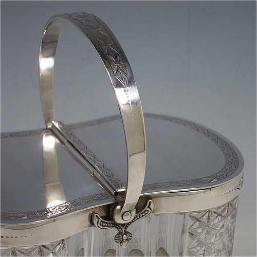 An Antique Victorian silver plated and cut crystal biscuit jar, having a hobnail and fluted cut crystal body, a hand-engraved mechanically double-hinged lid with a swing handle, and all sitting on a base with four cushion feet. Made by Thomas Wilkinson & Sons of Sheffield in ca. 1890. The dimensions of this fine hand-made antique silver-plated and hand-cut crystal biscuit jar are height inc. handle 23 cms (9 inches), length of base 19 cms (7.5 inches), and width of base 14 cms (5.5 inches).