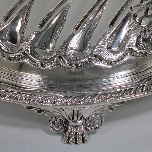An Antique Victorian Sterling Silver biscuit box, having a round straight-sided body with hand-chased fluting and floral decoration, a hinged lid with cast foliate finial, and sitting on an attached base plate with a gadroon border and three cast foliate & lions-paw feet. Made by William Hutton & Sons of London in 1899. The dimensions of this fine hand-made antique silver biscuit box are height 18 cms (7 inches), diameter at base 19 cms (7.5 inches), and it weighs approx. 744g (24 troy ounces).