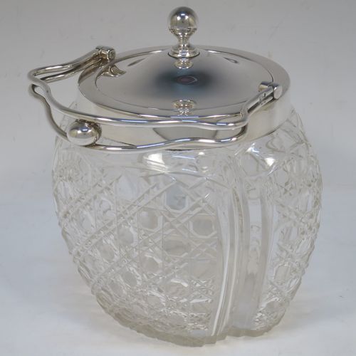 A pretty Antique Edwardian Sterling Silver and hand-cut crystal biscuit jar, having an unusual crystal body with hand-cut hobnail pattern panels with fluted corners, a plain round lift-off lid with a ball finial, a wire-work swing handle, and all sitting on a star-cut flat base. Made by Robert Pringle of London in 1904. The dimensions of this fine hand-made antique silver and crystal biscuit jar are height (excluding handle) 15 cms (6 inches), length 15 cms (6 inches), and width 13 cms (5 inches).