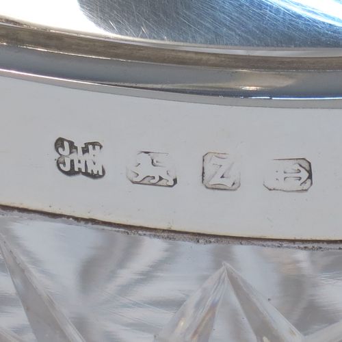 A very pretty and unusual Antique Victorian Sterling Silver and hand-cut crystal biscuit jar, having an oval crystal body with hand-cut hobnail and star-cut work, a plain oval mechanical lid which opens when moving the plain hinged swing-handle either left or right, and all sitting on a flat star-cut base. Made by Heath and Middleton of Birmingham in 1899. The dimensions of this fine hand-made antique silver and crystal biscuit jar are height (excluding handle) 13 cms (5 inches), length 16.5 cms (6.5 inches), and width 9 cms (3.5 inches).