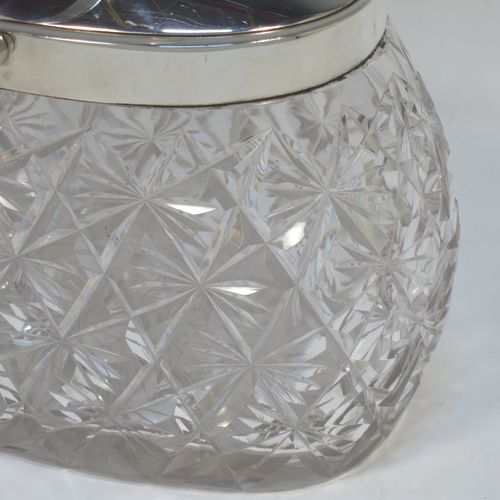 A very pretty and unusual Antique Victorian Sterling Silver and hand-cut crystal biscuit jar, having an oval crystal body with hand-cut hobnail and star-cut work, a plain oval mechanical lid which opens when moving the plain hinged swing-handle either left or right, and all sitting on a flat star-cut base. Made by Heath and Middleton of Birmingham in 1899. The dimensions of this fine hand-made antique silver and crystal biscuit jar are height (excluding handle) 13 cms (5 inches), length 16.5 cms (6.5 inches), and width 9 cms (3.5 inches).