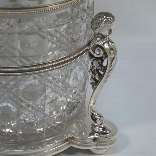 A very pretty Antique Victorian silver-plated and hand-cut crystal biscuit jar, having a hobnail and star cut body, a hinged lid with hand-engraved floral work and a cast leopards head finial, all sitting inside a galleried base with three cast caryatid figures attached to a central band and sitting on three cushion feet, all with bead-edge borders. Made by Henry Atkins of Sheffield in ca. 1880. The dimensions of this fine hand-made silver plated and crystal biscuit box are height 21.5 cms (8.5 inches), and diameter of base 15 cms (6 inches).