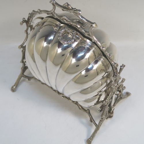 A beautiful Antique Victorian Silver Plated double folding biscuit box, having a plain shell-style body sitting in a cast tree branch designed frame, with a gold-gilt interior and original hand-pierced dividers. This very pretty antique plated biscuit box was made by James Dixon and Sons of Sheffield in ca. 1880. The dimensions of this fine hand-made antique silver-plated folding biscuit box are height 26 cms (10.25 inches), length fully opened 32 cms (12.5 inches), and width 20 cms (8 inches).