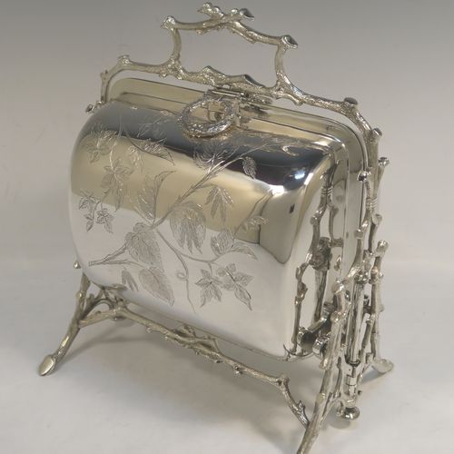 A very pretty Antique Victorian Silver Plated folding biscuit box, having an oval barrel-shaped body with beautiful hand-engraved floral decoration, sitting in a cast tree log style mechanical frame with carrying handle, and with original gold-gilt interior with hand-pierced dividers. This beautiful antique silver-plated folding biscuit box was made in ca. 1880. The dimensions of this fine hand-made silver-plated folding biscuit box are height 24 cms (9.5 inches), length fully opened 30.5 cms (12 inches), and width 20 cms (8 inches).   