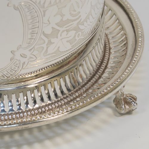 A very pretty Antique Victorian Silver-Plated biscuit box, having a round straight-sided body with bead-edged borders, hand-engraved floral decoration, a domed hinged lid with matching decoration and a cast round finial, and sitting on an attached base plate with three cast lions-paw  feet. This beautiful antique silver-plated biscuit box was made in ca. 1880. The dimensions of this fine hand-made antique silver-plated biscuit box are height 17 cms (6.75 inches), and diameter at base 18 cms (7 inches).   