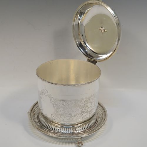 A very pretty Antique Victorian Silver-Plated biscuit box, having a round straight-sided body with bead-edged borders, hand-engraved floral decoration, a domed hinged lid with matching decoration and a cast round finial, and sitting on an attached base plate with three cast lions-paw  feet. This beautiful antique silver-plated biscuit box was made in ca. 1880. The dimensions of this fine hand-made antique silver-plated biscuit box are height 17 cms (6.75 inches), and diameter at base 18 cms (7 inches).   