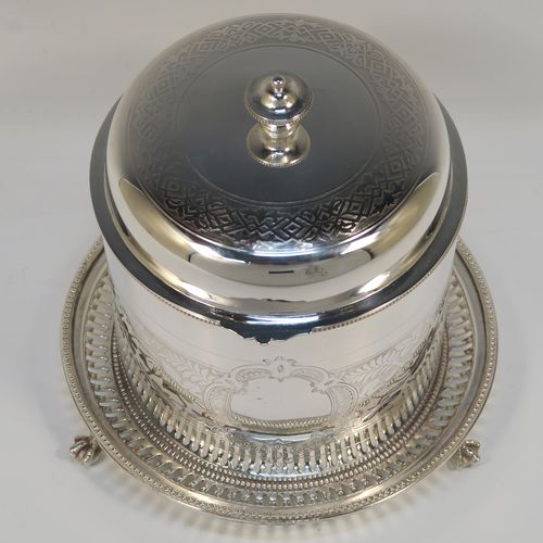 A very pretty Antique Victorian Silver-Plated biscuit box, having a round straight-sided body with bead-edged borders, hand-engraved floral decoration, a domed hinged lid with matching decoration and a cast round finial, and sitting on an attached base plate with three cast lions-paw  feet. This beautiful antique silver-plated biscuit box was made in ca. 1880. The dimensions of this fine hand-made antique silver-plated biscuit box are height 17 cms (6.75 inches), and diameter at base 18 cms (7 inches).   