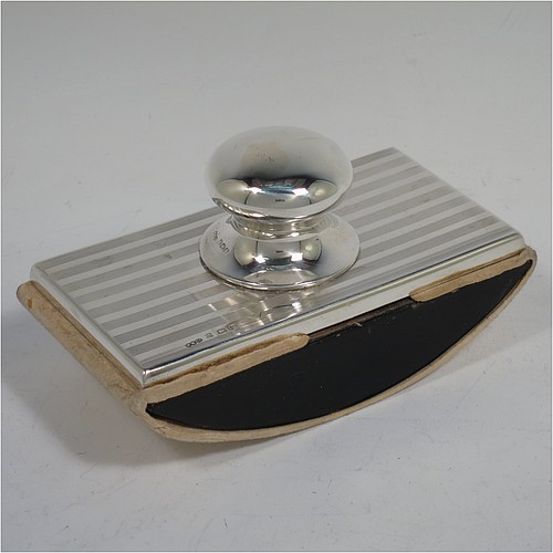 A Sterling Silver Rocker Blotter, having a rectangular body with engine-turned reeded decoration, a black stained wooden rocker base, and a plain round bellied handle that screws in to secure the rocker base and blotting paper to the upper body. Made by Wilmot Manufacturing Silversmiths of Birmingham in 1923. The dimensions of this fine hand-made silver rocker blotter are length 11.5 cms (4.5 inches), height 6.5 cms (2.5 inches), and width 6.5 cms (2.5 inches).