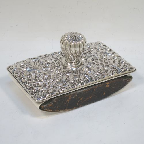 A very pretty Antique Edwardian Sterling Silver Rocker Blotter, having a rectangular body with rounded corners and hand-chased floral and scroll decoration, a leather covered rocker base, and a swirl fluted round handle that screws in to secure the rocker base and blotting paper to the upper body. Made by Henry Miller of Birmingham in 1902. The dimensions of this fine hand-made antique silver rocker blotter are length 11.5 cms (4.5 inches), height 6.5 cms (2.5 inches), and width 7 cms (2.75 inches).  