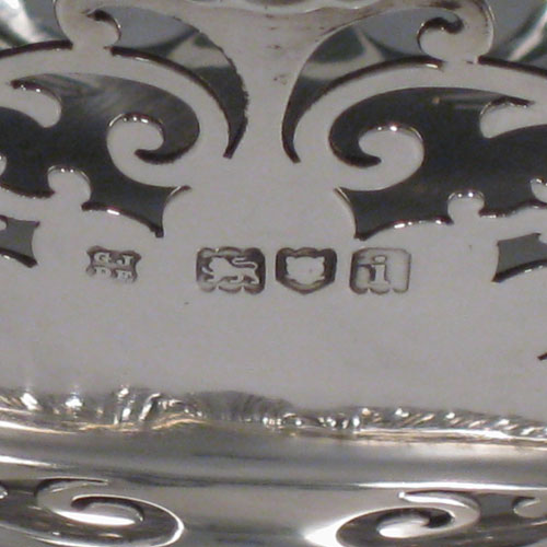 Antique Edwardian sterling silver bon-bon dish, having an oval hand-pierced body, applied shell and gadroon borders, cast shell and fluted handles, and sitting on a pedestal foot. Made by Jackson and Fullerton of London in 1904. Height 14 cms (5.5 inches), length 24 cms (9.5 inches), width 13 cms (5 inches). Weight approx. 383g (12.4 troy ounces).