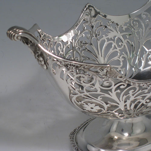 Antique Edwardian sterling silver bon-bon dish, having an oval hand-pierced body, applied shell and gadroon borders, cast shell and fluted handles, and sitting on a pedestal foot. Made by Jackson and Fullerton of London in 1904. Height 14 cms (5.5 inches), length 24 cms (9.5 inches), width 13 cms (5 inches). Weight approx. 383g (12.4 troy ounces).