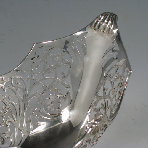 Antique Edwardian sterling silver bon-bon dish, having an oval hand-pierced body, applied shell and gadroon borders, cast shell and fluted handles, and sitting on a pedestal foot. Made by Jackson and Fullerton of London in 1904. Height 14 cms (5.5 inches), length 24 cms (9.5 inches), width 13 cms (5 inches). Weight approx. 383g (12.4 troy ounces).