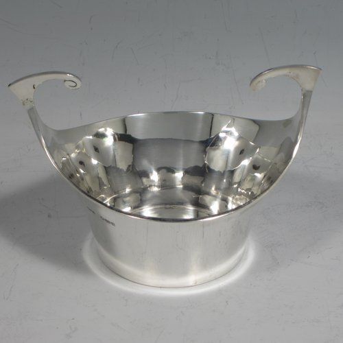 Antique Edwardian sterling silver pair of bon-bon dishes, having plain round bodies, with very unusual flying scroll handles, and each sitting on flat bases. Originally imported into, and hallmarked for, London in 1905. The dimensions of this fine pair of hand-made silver bon-bon dishes are width across handles 12 cms (4.75 inches), height 8 cms (3.25 inches), and they weigh a total of 180g (5.3 troy ounces).