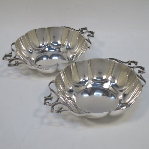 A very pretty Antique Edwardian Sterling Silver pair of bon-bon dishes, having rounded bodies with hand-chased lobed decoration, with beautiful scroll work side-handles, and all sitting on flat bases. Made by Roberts and Belk of Sheffield in 1908. The dimensions of this fine hand-made pair of antique silver bon-bon dishes  are length (inc. handles) 16 cms (6.25 inches), diameter 12 cms (4.75 inches), height 3.5 cms (1.3 inches), and they weigh a total of approx. 310g (10 troy ounces).   
