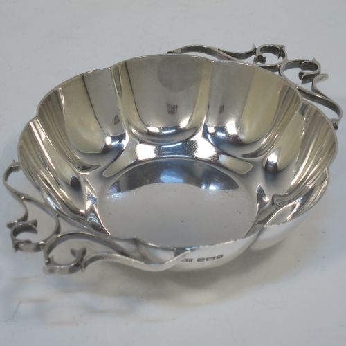 A very pretty Antique Edwardian Sterling Silver pair of bon-bon dishes, having rounded bodies with hand-chased lobed decoration, with beautiful scroll work side-handles, and all sitting on flat bases. Made by Roberts and Belk of Sheffield in 1908. The dimensions of this fine hand-made pair of antique silver bon-bon dishes are length (inc. handles) 16 cms (6.25 inches), diameter 12 cms (4.75 inches), height 3.5 cms (1.3 inches), and they weigh a total of approx. 310g (10 troy ounces).