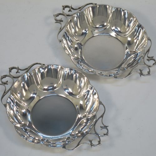 A very pretty Antique Edwardian Sterling Silver pair of bon-bon dishes, having rounded bodies with hand-chased lobed decoration, with beautiful scroll work side-handles, and all sitting on flat bases. Made by Roberts and Belk of Sheffield in 1908. The dimensions of this fine hand-made pair of antique silver bon-bon dishes are length (inc. handles) 16 cms (6.25 inches), diameter 12 cms (4.75 inches), height 3.5 cms (1.3 inches), and they weigh a total of approx. 310g (10 troy ounces).