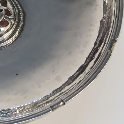 A beautiful and rare Antique Sterling Silver bon-bon dish, having a round hand-hammered body with an applied reeded border, a central applied and pierced Tudor rose with red enamelling and rope-twist border, and all sitting on a collet foot. This fantastic silver bon-bon dish was made by Omar Ramsden of London in 1924. The dimensions of this fine hand-made antique silver and enamelled dish are diameter 11 cms (4.3 inches), and it weigh approx. 87g (2.8 troy ounces). Importantly this item is engraved underneath with OMAR RAMSDEN ME FECIT.