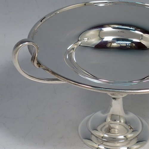 An Antique Edwardian Sterling Silver pair of bon-bon dishes, having plain round bodies, with applied reeded borders and two looped side handles, all raised above and sitting on plain round pedestal feet. Made by Holland, Aldwinkle & Slater of London in 1907. The dimensions of these fine hand-made antique silver bon-bon dishes are height 9 cms (3.5 inches), diameter 11.5 cms (4.5 inches), and they weigh a total of approx. 241g (7.8 troy ounces).