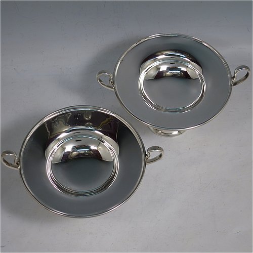 An Antique Edwardian Sterling Silver pair of bon-bon dishes, having plain round bodies, with applied reeded borders and two looped side handles, all raised above and sitting on plain round pedestal feet. Made by Holland, Aldwinkle & Slater of London in 1907. The dimensions of these fine hand-made antique silver bon-bon dishes are height 9 cms (3.5 inches), diameter 11.5 cms (4.5 inches), and they weigh a total of approx. 241g (7.8 troy ounces).