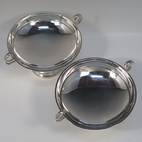 A very handsome and large pair of Antique Sterling Silver bon-bon dishes, having plain round bodies, with applied reeded borders and two scroll side handles, all raised above and sitting on plain round pedestal feet. This elegant pair of silver dishes were made by Walker and Hall of Sheffield  in 1912. The dimensions of these fine hand-made antique silver bon-bon dishes are height 12.5 cms (5 inches), diameter 15 cms (6 inches), and they weigh a total of approx. 520g (16.8 troy ounces).   