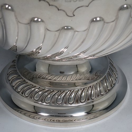 An Antique Victorian Sterling Silver large table bowl, having a round body with an applied reeded border and hand-chased half swirl-fluted decoration, all sitting on a pedestal foot which is also fluted. Made by Sibray, Hall & Co., of London in 1897. The dimensions of this fine hand-made antique silver bowl are diameter 25.5 cms (10 inches), height 19 cms (7.5 inches), and it weighs approx. 1,041g (33.6 troy ounces).