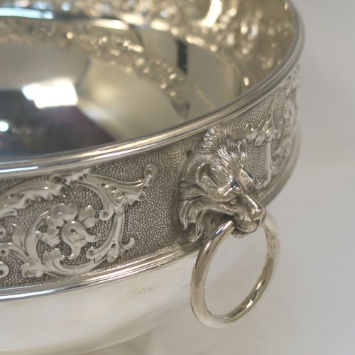 A very pretty antique Victorian Silver Plated table bowl, having a round bellied body with a hand-chased upper band of floral and scroll work with vacant cartouches, with two cast lion-mask ring side-handles, and sitting on a round plain pedestal foot. This beautiful antique silver-plated fruit bowl was made in Sheffield in ca. 1880. The dimensions of this fine hand-made antique silver plated table bowl are diameter 25.5 cms (10inches), and height 16 cms (6.3inches).
