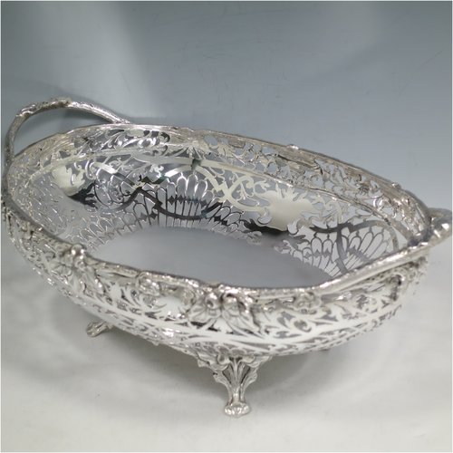 A Sterling Silver large table bowl, having an oval body with hand-pierced floral decoration, an applied cast border with oak-leaf mounts, with two cast loop handles, and all sitting on four cast foliate feet with matching decoration. Made by Robert Pringle of Sheffield in 1951. The dimensions of this fine hand-made silver bowl are length 32 cms (12.5 inches), width 20 cms (8 inches), height 14 cms (5.5 inches), and it weighs approx. 898g (29 troy ounces).   