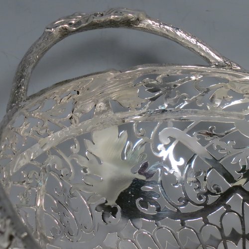A Sterling Silver large table bowl, having an oval body with hand-pierced floral decoration, an applied cast border with oak-leaf mounts, with two cast loop handles, and all sitting on four cast foliate feet with matching decoration. Made by Robert Pringle of Sheffield in 1951. The dimensions of this fine hand-made silver bowl are length 32 cms (12.5 inches), width 20 cms (8 inches), height 14 cms (5.5 inches), and it weighs approx. 898g (29 troy ounces).
