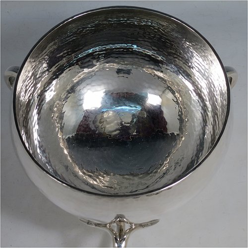 An Antique Edwardian heavy Sterling Silver Art Nouveau style table bowl, having a round hand-hammered and bellied body, with three cast scroll and tendril handles attached to a pedestal foot. Made by the Barker Brothers of Chester in 1909. The dimensions of this fine hand-made antique silver bowl are height 15 cms (6 inches), diameter at top of bowl 20 cms (8 inches), and it weighs approx. 44 troy ounces (1,370g).