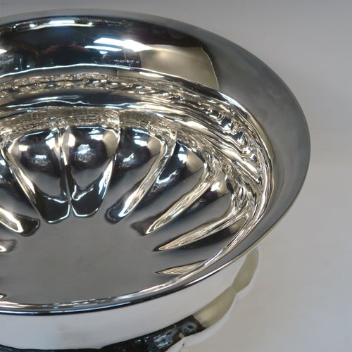 A rare and very elegant Antique late Georgian Sterling Silver large table bowl, having a round bellied body with a lower band of hand-chased melon-style fluting, and all sitting on a round pedestal foot. This beautiful antique silver table bowl was made by Joseph Cradock of London in 1828. The dimensions of this fine hand-made antique silver bowl are diameter 30.5 cms (12 inches), height 18.5 cms (7.3 inches), and it weighs approx. 1,222g (39.4 troy ounces).