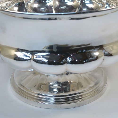 A rare and very elegant Antique late Georgian Sterling Silver large table bowl, having a round bellied body with a lower band of hand-chased melon-style fluting, and all sitting on a round pedestal foot. This beautiful antique silver table bowl was made by Joseph Cradock of London in 1828. The dimensions of this fine hand-made antique silver bowl are diameter 30.5 cms (12 inches), height 18.5 cms (7.3 inches), and it weighs approx. 1,222g (39.4 troy ounces).