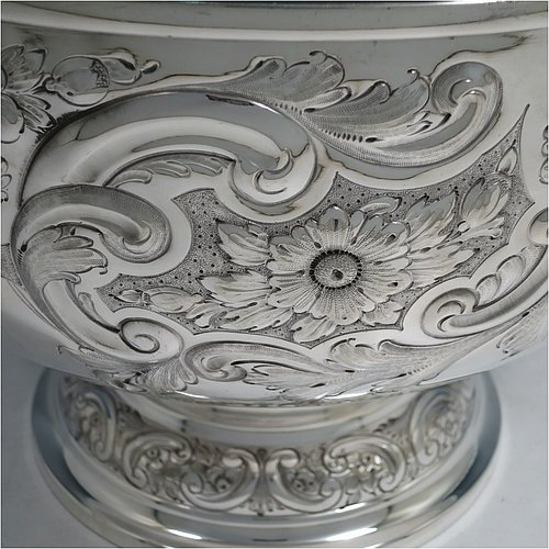 An Antique Victorian Silver Plated large table bowl, having a round hand-chased body with floral and scroll-work decoration, an applied plain border, with two vacant cartouches either side of the body, and sitting on a pedestal foot. Made in ca. 1880. The dimensions of this fine hand-made antique silver-plated table bowl are diameter 30.5 cms (15 inches), and height 21.5 cms (8.5 inches).
