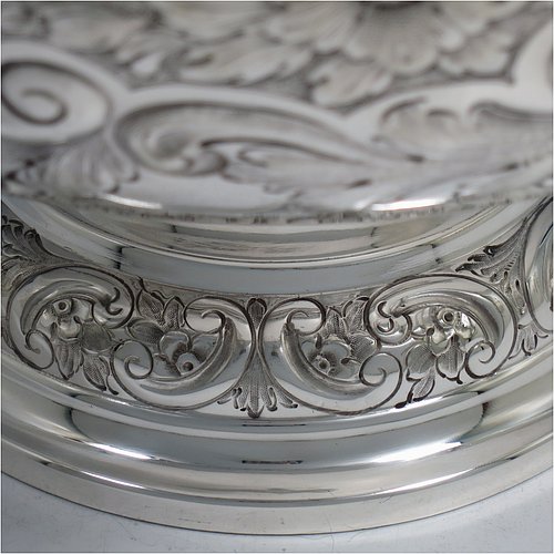 An Antique Victorian Silver Plated large table bowl, having a round hand-chased body with floral and scroll-work decoration, an applied plain border, with two vacant cartouches either side of the body, and sitting on a pedestal foot. Made in ca. 1880. The dimensions of this fine hand-made antique silver-plated table bowl are diameter 30.5 cms (15 inches), and height 21.5 cms (8.5 inches).