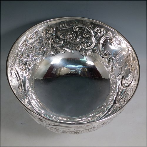 An Antique Victorian Silver Plated large table bowl, having a round hand-chased body with floral and scroll-work decoration, an applied plain border, with two vacant cartouches either side of the body, and sitting on a pedestal foot. Made in ca. 1880. The dimensions of this fine hand-made antique silver-plated table bowl are diameter 30.5 cms (15 inches), and height 21.5 cms (8.5 inches).