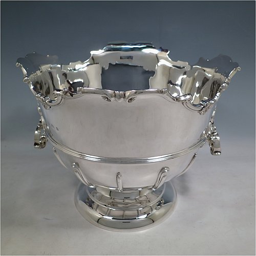 An Antique Edwardian Sterling Silver large table bowl, having a round body with an applied shell and scroll border, an applied reeded central band, together with cast hinged side-handles, and with applied strap-work on the lower body, and all sitting on a pedestal foot. Made by Williams of Birmingham in 1909. The dimensions of this fine hand-made large silver table bowl are diameter 29 cms (11.5 inches), height 23.5 cms (9.25 inches), and it weighs approx. 2,123g (68.5 troy ounces).    