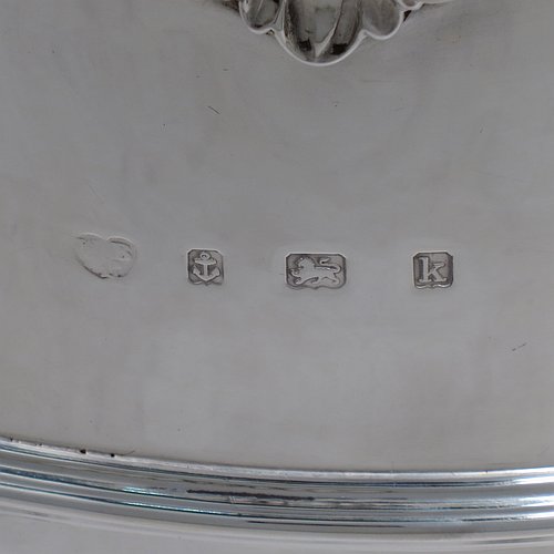 An Antique Edwardian Sterling Silver large table bowl, having a round body with an applied shell and scroll border, an applied reeded central band, together with cast hinged side-handles, and with applied strap-work on the lower body, and all sitting on a pedestal foot. Made by Williams of Birmingham in 1909. The dimensions of this fine hand-made large silver table bowl are diameter 29 cms (11.5 inches), height 23.5 cms (9.25 inches), and it weighs approx. 2,123g (68.5 troy ounces).