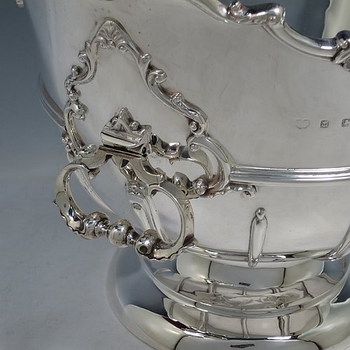An Antique Edwardian Sterling Silver large table bowl, having a round body with an applied shell and scroll border, an applied reeded central band, together with cast hinged side-handles, and with applied strap-work on the lower body, and all sitting on a pedestal foot. Made by Williams of Birmingham in 1909. The dimensions of this fine hand-made large silver table bowl are diameter 29 cms (11.5 inches), height 23.5 cms (9.25 inches), and it weighs approx. 2,123g (68.5 troy ounces).
