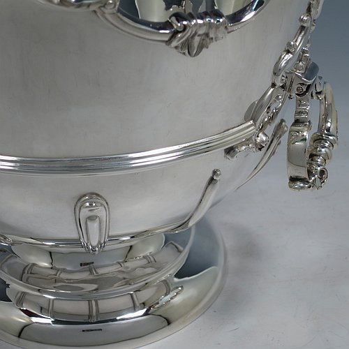An Antique Edwardian Sterling Silver large table bowl, having a round body with an applied shell and scroll border, an applied reeded central band, together with cast hinged side-handles, and with applied strap-work on the lower body, and all sitting on a pedestal foot. Made by Williams of Birmingham in 1909. The dimensions of this fine hand-made large silver table bowl are diameter 29 cms (11.5 inches), height 23.5 cms (9.25 inches), and it weighs approx. 2,123g (68.5 troy ounces).