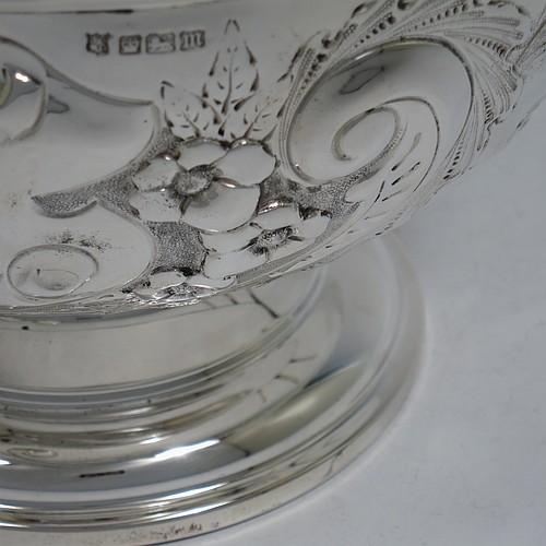 A very pretty Antique Edwardian Sterling Silver large table bowl, having a round body with an applied reeded border and hand-chased floral and scroll decoration, with two vacant cartouches either side, a gold-gilt interior, and all sitting on a stepped pedestal foot. Made by the Deakin Brothers of Sheffield in 1904. The dimensions of this fine hand-made antique silver bowl are diameter 25.5 cms (10 inches), height 15 cms (6 inches), and it weighs approx. 780g (25 troy ounces).